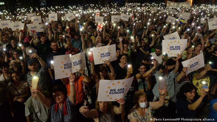 Demonstrators hold banners and lights during a public rally in front of the Parliamentary building in Tbilisi, Georgia