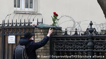 Мужчина оставляет розу на воротах украинского посольства в Москве, поверх которых колючая проволока