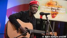 Bobi Wine spielt Gitarre und singt. Er trägt eine rote Baskenmütze. 
