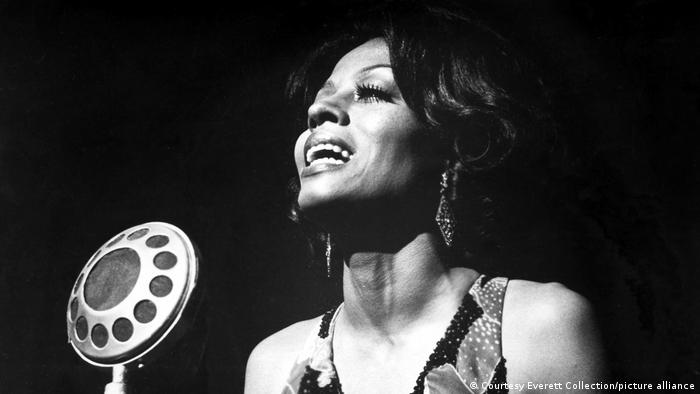 Diana Ross as Billie Holliday sings into a microphone.