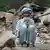 Старик-афганец сидит на развалинах после землетрясения