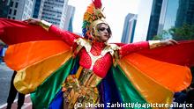 Stolz breitet dieser Teilnehmer die regenbogenfarbenen Flügel seines fantasievollen Kostüms aus, auf der Pride Parade 2022 in São Paulo.
