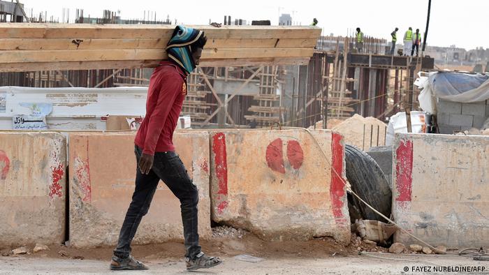 A man carries a load of wood at a construction site