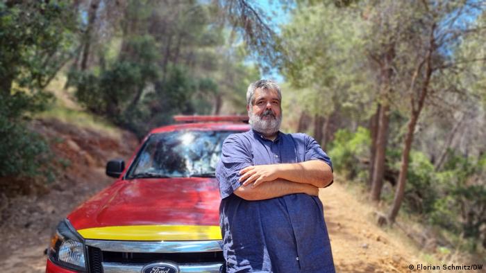 Stavros Salayiannis stands in front of his red Ford pick-up on a fire trail in the woods near Vyronas, Greece