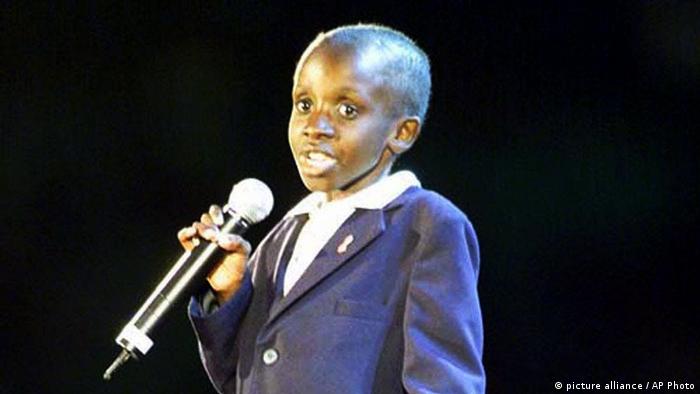 A child in a suit speaks into a microphone