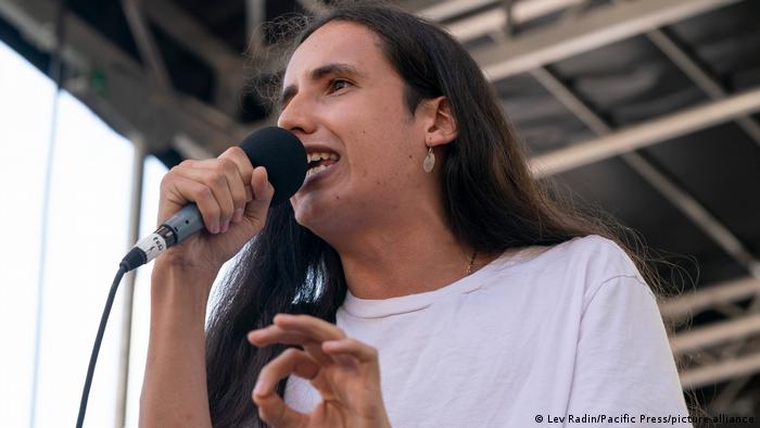 Picture of a long-haired person speaking into a microphone
