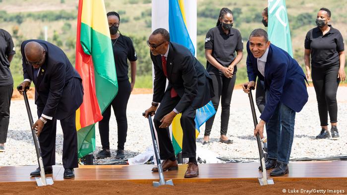 Ghana president Akufo-Addo, Rwanda's president Paul Kagame and the CEO of BioNTech, Ugur Sahin shovel dirt in front of flags