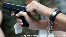 Sally Abrahamsen, of Pompano Beach, Fla., right, holds a Glock 42 pistol while shopping for a gun at the National Armory gun store and gun range, Tuesday, Jan. 5, 2016, in Pompano Beach, Fla. President Barack Obama unveiled his plan Tuesday to tighten control and enforcement of firearms in the U.S. At left is salesperson T.J. O'Reilly. (AP Photo/Lynne Sladky)
