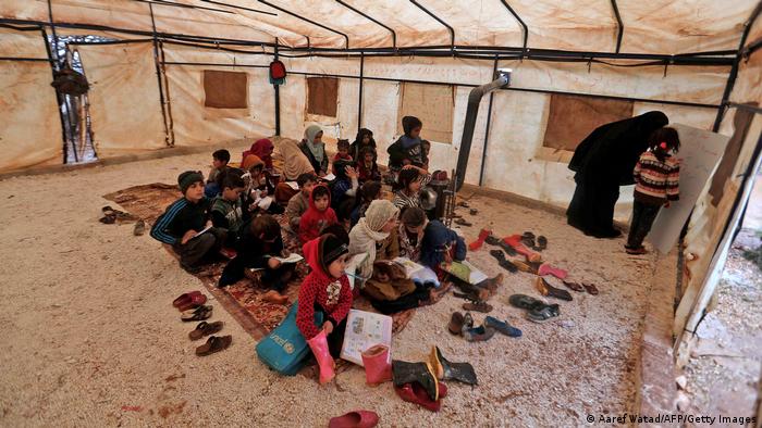 A volunteer teaches students in a make-shift classroom at a camp for the displaced by the village of Killi, near Bab al-Hawa by the border with Turkey.