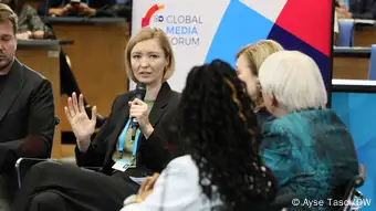 Ukrainian journalist Angelina Kariakina talks into the microphone and looks towards her fellow panelists Věra Jourová and Claudia Roth at the 2022 conference discussion on journalism in wartimes.