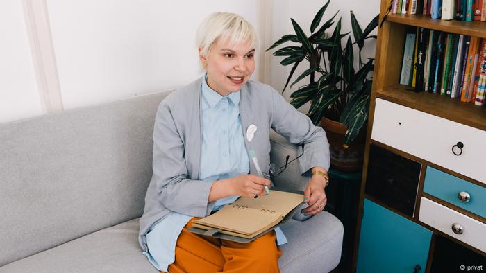 Psychologist Maria Potudina sits on a sofa with a pen in her hand