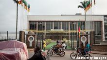 People walk by the Cameroon's parliament on November 17, 2017 in Yaounde, after a fire swept through the main building overnight, causing substantial damage. / AFP PHOTO / - (Photo credit should read -/AFP via Getty Images)