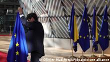 Ein Mitglied des Protokolls drappiert Fahnen vor der Ankunft zu einem EU-Gipfel. Die Staats- und Regierungschefs der 27 EU-Mitgliedstaaten kommen in Brüssel zu einem zweitägigen Treffen zusammen, bei dem sie über die Gewährung des EU-Kandidatenstatus für die Ukraine und Moldau sowie über ein Treffen mit den Ländern des westlichen Balkans beraten werden. +++ dpa-Bildfunk +++