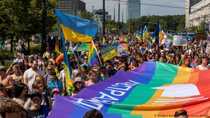 Participants in the march holding Ukrainian flags alongside rainbow flags