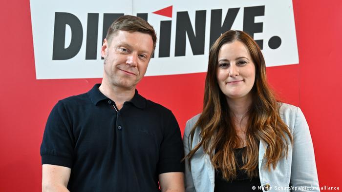 Martin Schirdewan (l.) und Janine Wissler lächeln vor einem Logo der Partei Die Linke in die Kamera