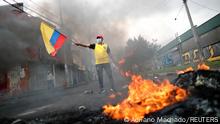 A demonstrator holds up a flag of Ecuador next to a fire, as protesters block the street during an anti-government protest amid a stalemate between the government of President Guillermo Lasso and largely indigenous demonstrators who demand an end to emergency measures, in Quito, Ecuador June 24, 2022. REUTERS/Adriano Machado