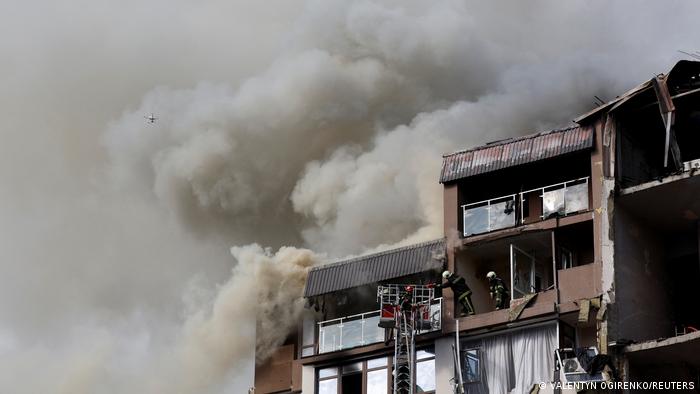 Firefighters work to put out a fire as smoke rises from residential building damaged by a Russian missile strike
