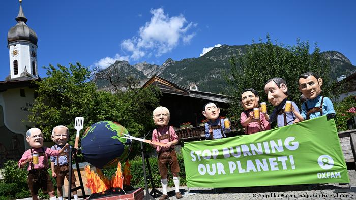 Protesters dressed up as world leaders holding a banner that reads stop burning our planet