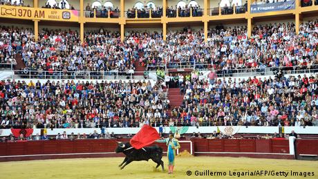 Colobian bullfighter and bull at a packed stadium