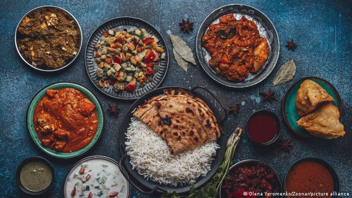 Various Indian specialties on a platter decorated with spices; among them rice and chapati and various sauces, curries and vegetables