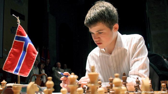 Der junge Magnus Carlsen bei einem Schachspiel. Links im Bild eine norwegische Flagge.