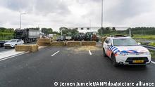 27.06.2022, Niederlande, Best: Traktoren stehen während eines Protests auf der mit Strohballen blockierten Autobahn A2. Aus Protest gegen geplante Umweltauflagen haben Bauern in den Niederlanden mehrere Autobahnen blockiert. Foto: JEROEN JUMELET/ANP/dpa +++ dpa-Bildfunk +++