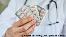 Hand von Arzt in einer Klinik hält Tabletten in Blisterpackung als neue Therapie