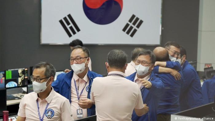 Men hug in front of a South Korean flag