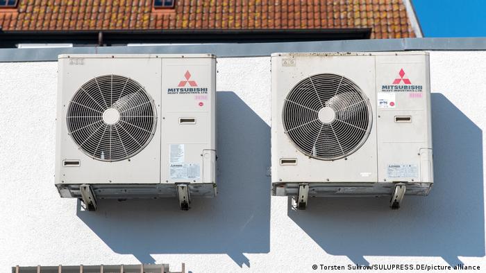 Two air conditioners hang on a wall