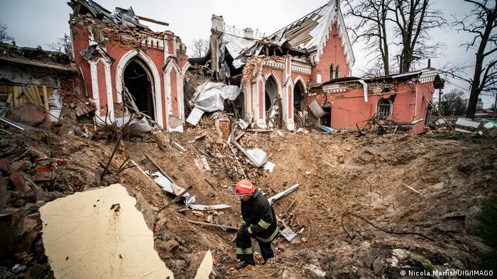 La destruida Biblioteca Juvenil de Chernígov, con un bombero en primer plano.