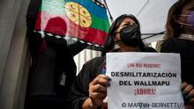 Members of the constituent convention and supporters of the Mapuche people demonstrate with a Mapuche flag and a sign reading “Demilitarization” in rejection of the militarization of the Araucania region in southern Chile, during a march outside La Moneda Palace, in Santiago, November 4, 2021. - A Mapuche indigenous man died and five others were injured Wednesday during clashes with the police and military in Arauco province, southern Chile, in an area under state of emergency. (Photo by Martin BERNETTI / AFP)