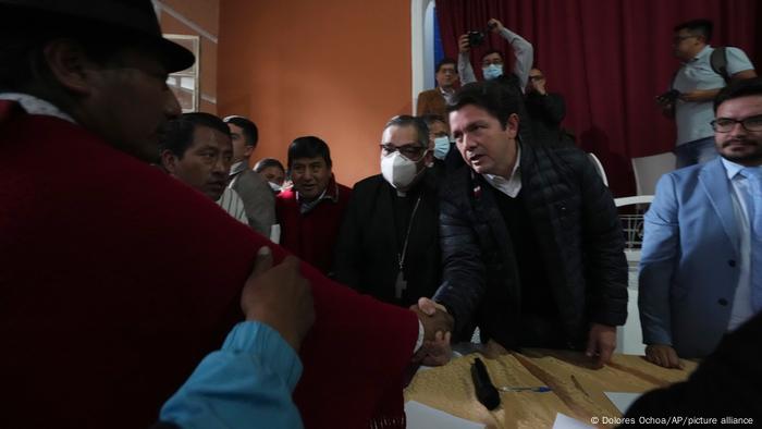 Indigenous leader Leonidas Iza, left, shakes hands with Government Minister Francisco Jimenez after reaching an agreement with mediation by the church at the Episcopal Conference headquarters in Quito, Ecuador, Thursday, June 30, 2022. 