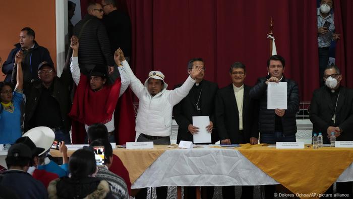 Government representative Francisco Jimenez holds up the agreement made with Indigenous leaders, Eustaquio Toala, third from left, and Leonidas Iza, third from left, as they stand with Catholic Church representatives who served as mediators at the Episcopal Conference headquarters in Quito, Ecuador, Thursday, June 30, 2022.