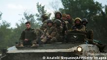 Ukrainian soldiers ride on an armored personnel carrier (APC) on a road of the eastern Luhansk region on June 23, 2022, amid Russia's military invasion launched on Ukraine. - On the road between the towns of Siversk and Bakhmut, AFP journalist witnessed several shellings on the route, which is now the main itinerary being used to reach the city of Lysychansk, since a highway has long been under shelling. Driving out of the devastated eastern Ukrainian city of Lysychansk on June 23, the journalists twice had to jump out of cars and lie on the ground as Russian forces shelled the city's main supply road. The three shelling incidents they witnessed took place on a stretch of road approximately 5 kilometres (3 miles) long. (Photo by Anatolii Stepanov / AFP) (Photo by ANATOLII STEPANOV/AFP via Getty Images)