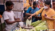 A woman buying cobs of corn in a plastic bag