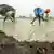 Los dos trabajadores agachados y con los pies cubiertos por el agua van clavando en la tierra anegada las plantas de arroz.
