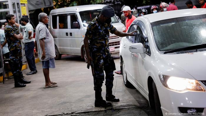 A Sri Lanka Air Force member checks the tokens of people queueing for fuel due to fuel shortage, amid the country's economic crisis, in Colombo, Sri Lanka