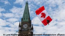 A Skyhawk member glides beside the Peace tower during Canada Day events in Ottawa, Ontario, on Friday July 1, 2022. (Lars Hagberg/The Canadian Press via AP)