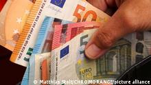 A person holds several euro notes