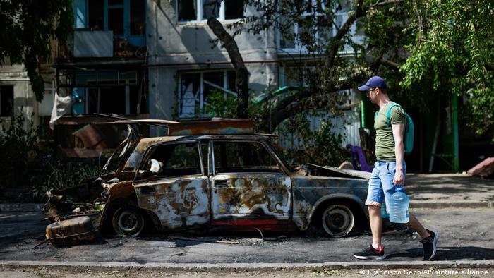 Un hombre transporta agua frente a un edificio de apartamentos dañado por un ataque nocturno con misiles, en Sloviansk, Ucrania, el 31 de mayo de 2022.