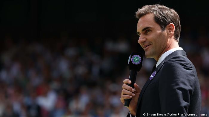 Roger Federer habla por el micrófono en la pista central para la celebración de los 100 años.