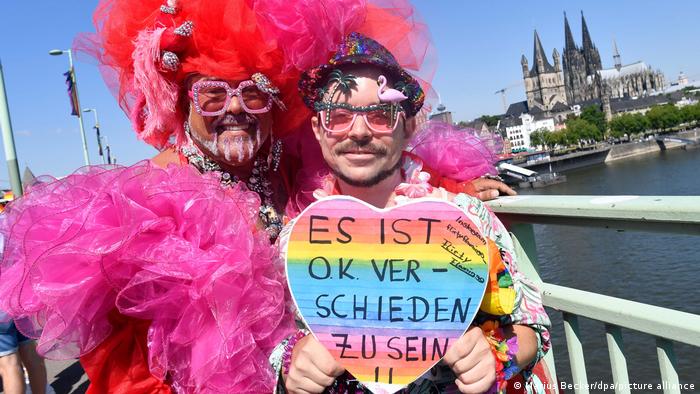 Vor dem Kölner Dom halten Protestierende ein Schild mit der Aufschrift: Es ist o.k. verschieden zu sein