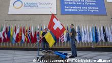 Daniel May, staff member of the Swiss confederation, left, and a collegue prepare the flags of Ukraine, left, and Switzerland, ahead of the Ukraine Recovery Conference URC, Sunday, July 3, 2022 in Lugano, Switzerland. The URC is taking place from Monday and Tuesday, July 4 and 5 to initiate the political process for the recovery of Ukraine after the attack of Russia to its territory. (KEYSTONE/EDA/Pascal Lauener)