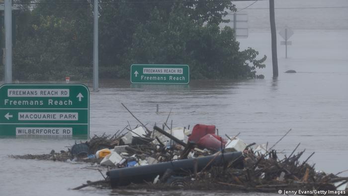 Street signs stick to the flooded street and debris floats