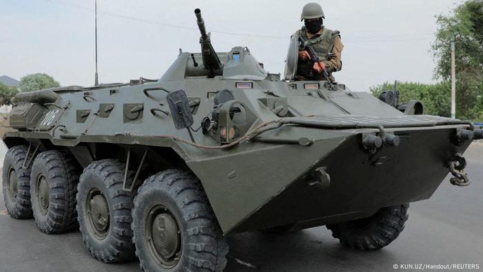 An Uzbek soldier in a combat vehicle holds an assault rifle on a street in Nukus