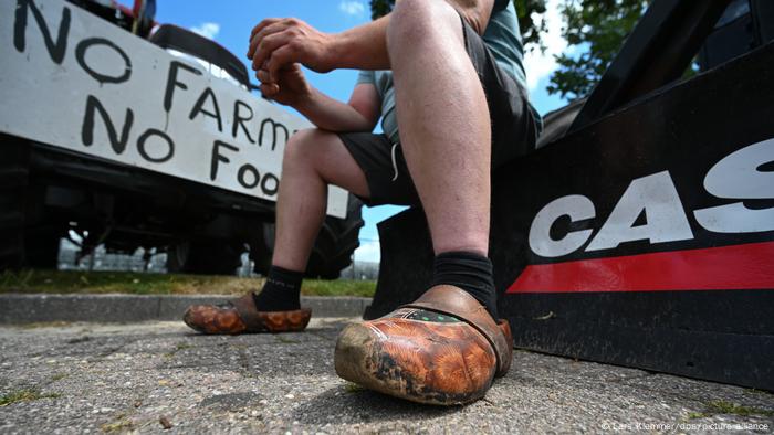 A farmer sits in front of his tractor in classic wooden clogs as part of a protest against planned environmental regulations