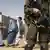 Soldat mit Maschinenpistole, im Hintergrund verschleierte Frauen (Foto: AP)