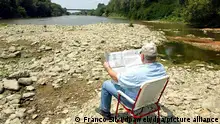 An unidentified man reads the newspaper on Friday 18 July 2003, as he sits in the dried up river bed of the river Arno near the town of Pisa, Italy. Authorities were urging Italians to limit consumption of water and electricity as the prolonged drought had all but dried up some of the country's most important rivers, threatening agriculture and jeopardizing the production of electricity by thermoelectric power plants. Foto: Foto Franco Silvi dpa +++ dpa-Bildfunk +++