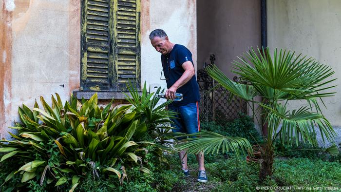 Un hombre riega las plantas de su jardín con una botella de agua mineral. 