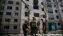 Soldiers stand outside a shelled building